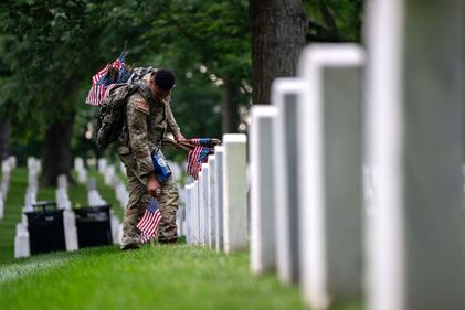 ARLINGTON, VIRGINIA - MAY 23: Members of the 3rd U.S. Infantry Regiment, also known as the "Old Guard," place flags at the headstones of U.S. military personnel buried at Arlington National Cemetery ahead of Memorial Day, on May 23, 2024 in Arlington, Virginia. Nearly 1,500 joint service members will spend around four hours placing small American flags in front of more than 260,000 headstones. The cemetery, consisting of 639 acres, is the final resting place of approximately 400,000 veterans and their dependents. (Photo by Kent Nishimura/Getty Images)